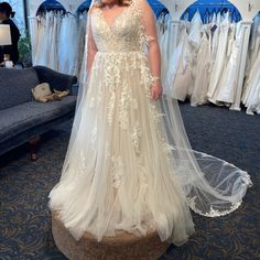 a woman in a wedding dress standing next to a couch and looking at the camera