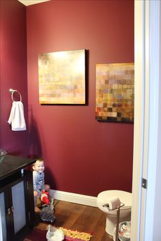 a bathroom with red walls and wooden floors