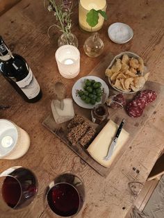 a wooden table topped with lots of food and wine