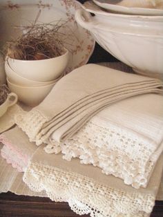 there are many plates and bowls on the table with lace doily around them,