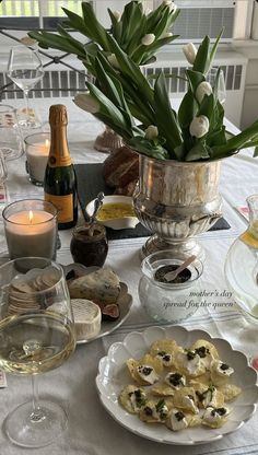 a table topped with plates and glasses filled with food next to bottles of wine on top of a white table cloth