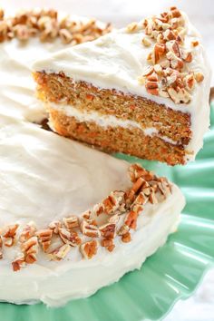 a slice of carrot cake with white frosting and pecans is on a green plate