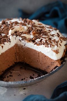 a chocolate pie with white frosting and chopped nuts on top is sitting on a plate