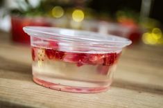 a plastic container filled with fruit sitting on top of a wooden table