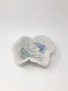 a white and blue flower shaped dish on a white tablecloth with watercolor splatters