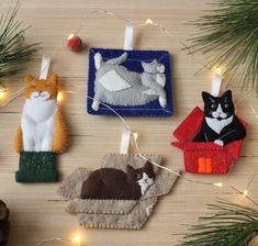 four felt ornaments hanging from a christmas tree with lights on the branches and decorations around them