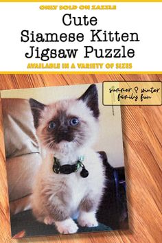 a cat sitting on top of a wooden floor next to a sign that says cute siamese kitten jigaw puzzle