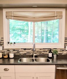 a kitchen sink under a window next to a dishwasher