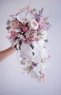 a woman holding a bouquet of flowers in her hand with white and pink blooms on it