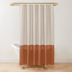 an orange and white shower curtain with gold hardware on the bottom, in front of a bathtub