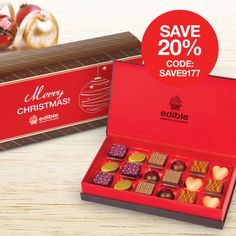 a red box filled with assorted chocolates next to a christmas ornament