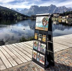 a sign on the side of a wooden dock next to a body of water with mountains in the background