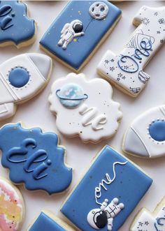 some cookies that are laying on top of a white tablecloth with blue and white icing