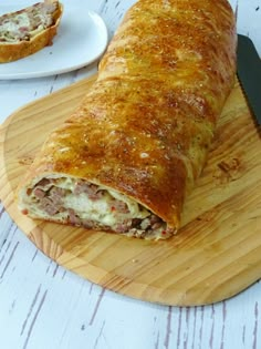 a wooden cutting board topped with a meat filled pastry