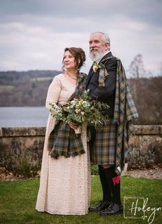 an older man and woman standing next to each other in front of a body of water