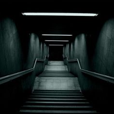 an empty staircase leading up to the second floor in a dark room with light coming from above