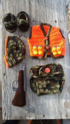 crocheted items are laid out on a wooden table, including an orange vest and hat