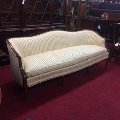 a white couch sitting on top of a red carpeted floor next to wooden furniture