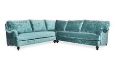 a blue velvet sectional sofa sitting on top of a white floor