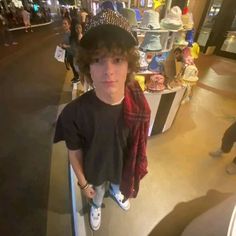 a young boy wearing a hat and standing in front of a counter at a store