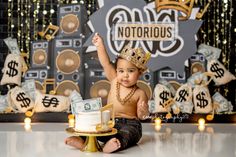 a baby sitting on the floor with a cake and money in front of him, wearing a gold crown