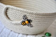 a white basket with a yellow and black bee on the side next to green buttons