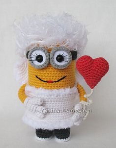 a crocheted minion holding a red heart