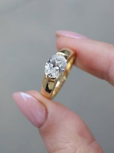 a woman's hand holding a yellow gold ring with a diamond in the middle