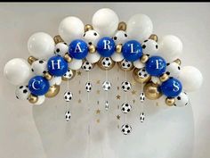 a bunch of balloons that are hanging on the wall with letters and soccer balls attached to them