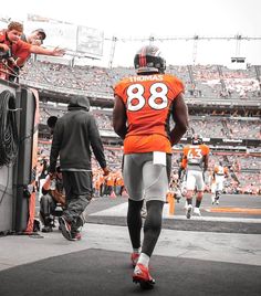 a football player in an orange jersey walking onto the field