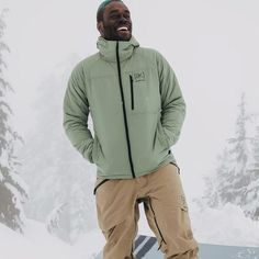 a man standing on top of a snowboard in front of some trees and snow