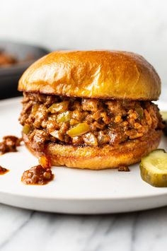 a sloppy joe sandwich with pickles on the side