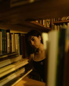 a woman standing in front of a book shelf filled with books