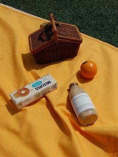 an orange sitting on top of a yellow blanket next to a bottle of toothpaste