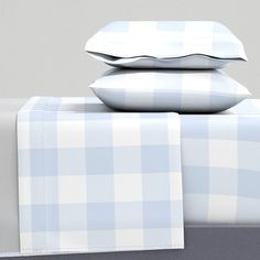 three pillows stacked on top of each other next to a bed sheet and pillow case