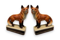 two small figurines of foxes on marble bases