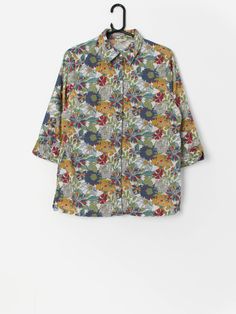 Vintage Y2K floral shirt. This beautiful and vibrant Y2K shirt features an iridescent button closure, three quarter sleeves and a split, flowing hem. Made from a lightweight cotton.  Our recommended size: Medium Label says: 12 Condition: Very good Material: 100% cotton Measurements in inches: Pit to pit: 20 Shoulders: 15.5 Front length: 27.5 Back length: 26.5 Sleeve: 17.5 Hem: 21 We recommend that you compare our measurements to a similar item of your own to ensure good fit. Measurements are tak Relaxed Fit Blouse With Roll-up Sleeves For Spring, Summer Tops With Roll-up 3/4 Sleeves, Spring Patterned Shirt With Relaxed Fit, Patterned Relaxed Fit Shirt For Spring, Patterned Shirt With Relaxed Fit For Spring, Relaxed Fit Patterned Shirt For Spring, Multicolor Half Sleeve Blouse For Summer, Relaxed Fit Half Sleeve Floral Print Tops, Relaxed Fit Floral Print Half Sleeve Tops