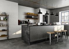 an industrial style kitchen with stainless steel counter tops and stools in front of the bar