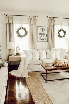 a living room with white furniture and christmas wreaths on the window sill,