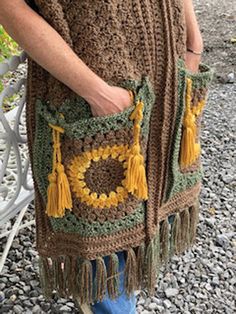 a woman is wearing a crocheted shawl with tassels on it