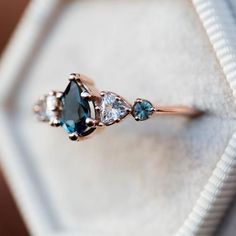 an engagement ring with three pear shaped blue topaztes and diamond accents on it