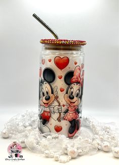 a glass jar with mickey and minnie mouses painted on the side, surrounded by beads