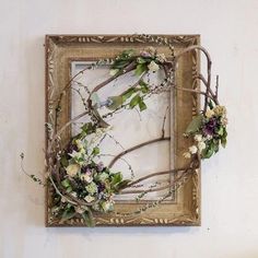 a frame with branches and flowers hanging on the wall