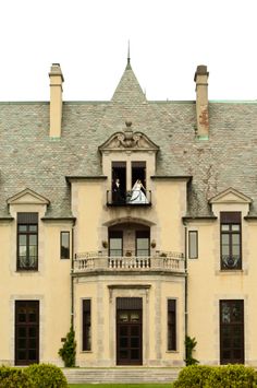 a bride and groom standing on the balcony of an old mansion