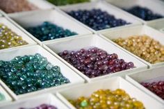 many different colors of beads in white bowls