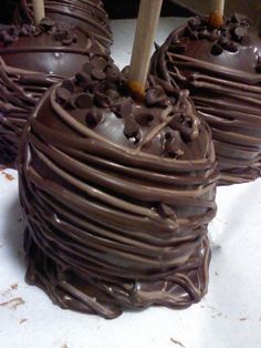 three chocolate covered apples sitting on top of a white tablecloth with candles in the shape of hearts