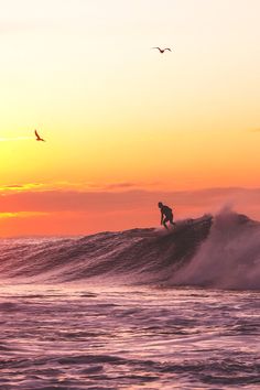 a person on a surfboard riding a wave at sunset