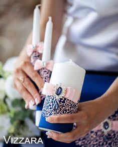 the bride is holding three candles in her hands and wearing blue, pink and white