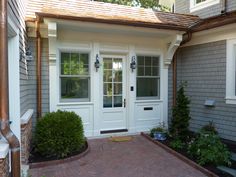 a house with two white doors and brick walkway