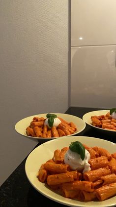 three white plates filled with food on top of a black counter next to a wall